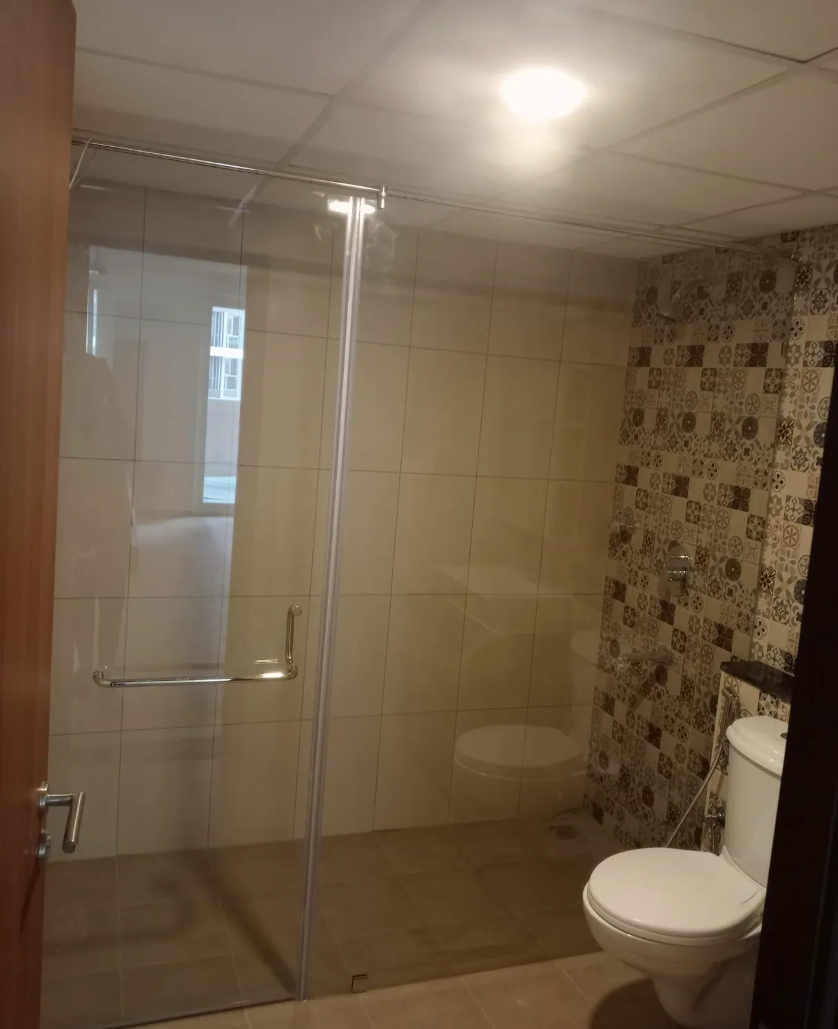 Sliding glass shower cubicle in grey tiled bathroom Bangalore