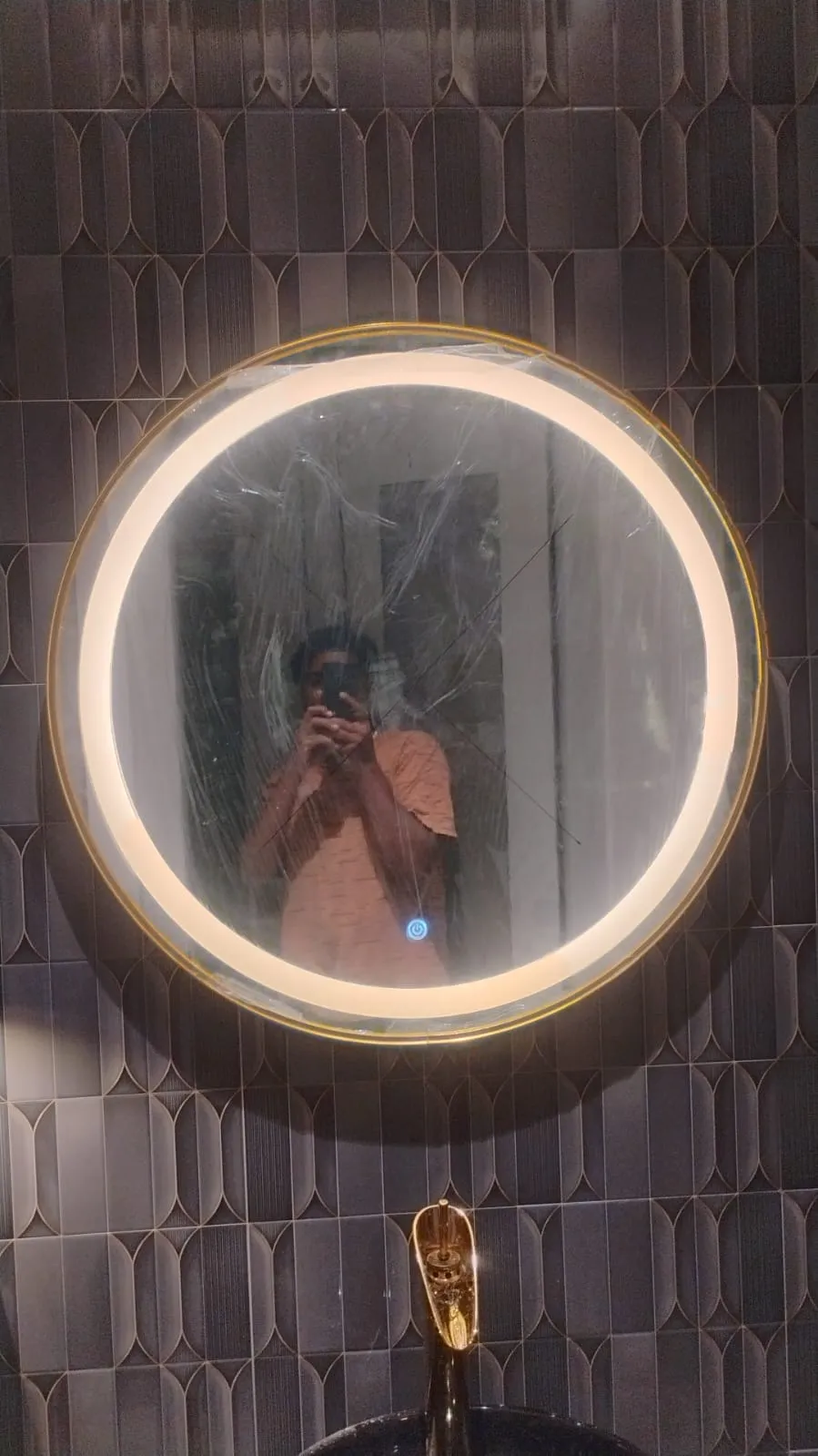 Round LED backlit mirror with gold frame in dark bathroom Bangalore